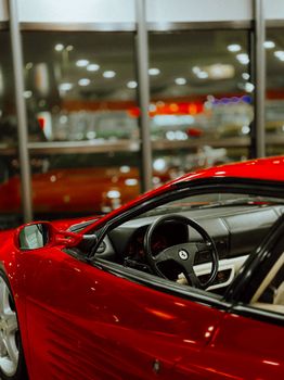 Close-up of a luxurious red sports car interior in a sleek, modern showroom setting.
