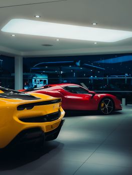 Showroom with two luxury sports cars under soft lighting, showcasing sleek design.